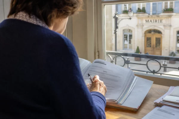 Élu local anonyme prenant des notes sur un dossier dans une mairie française lumineuse