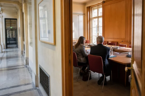 Hall lumineux d’une institution française avec salle d’audition, dossiers et fonctionnaires anonymes en discussion