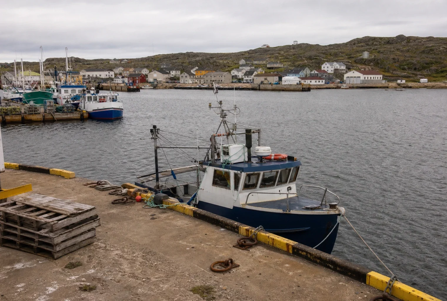 Quai de Saint-Pierre avec bateaux et maisons basses, sur fond de côte rocheuse de l’archipel.