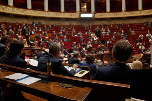Dans l’hémicycle de l’Assemblée nationale, des députés sont assis derrière leurs pupitres pendant une séance.