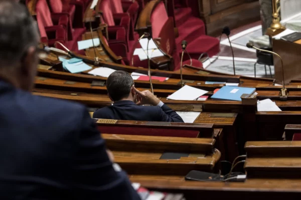 L’hémicycle de l’Assemblée nationale avec ses pupitres et micros, cadre sobre pour un sujet politique et judiciaire.