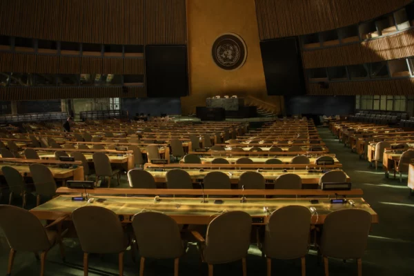 Salle de l’Assemblée générale de l’ONU à New York, avec pupitres, micros et rangées de sièges.
