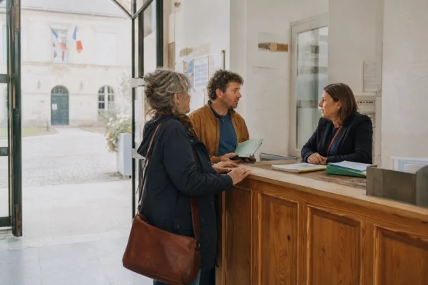 Citoyens échangeant avec un élu anonyme dans le hall lumineux d’une mairie française