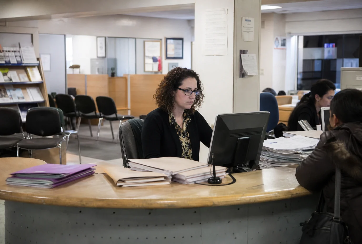 Guichet d’un bailleur social avec dossiers de demande et chaises d’attente, dans un bureau administratif français.
