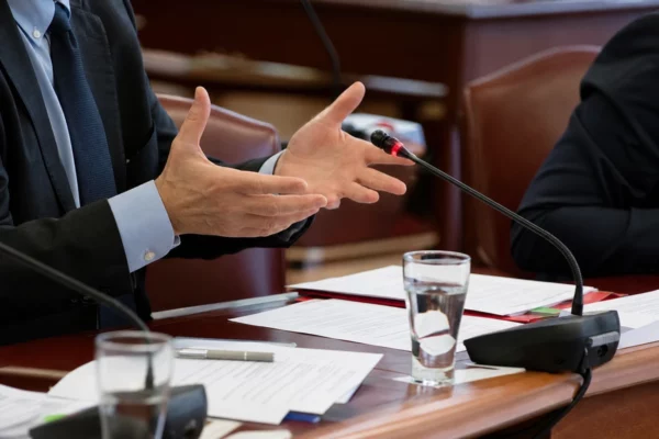 Salle d’audition au Sénat avec micros, tables et dossiers, pendant une mission d’information sur les violences périscolaires.