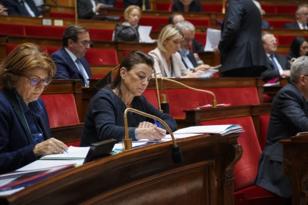 Dans l’hémicycle de l’Assemblée nationale, des pupitres et dossiers évoquent le débat budgétaire sur l’aide à l’Ukraine.