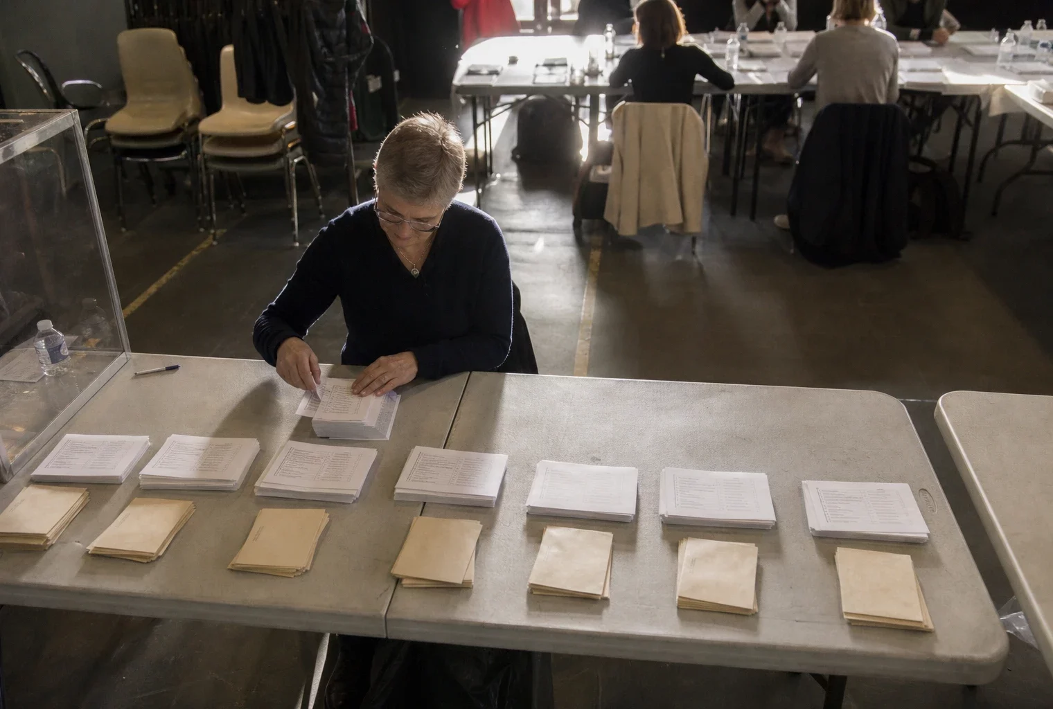Des bulletins de vote de liste sont triés sur une table lors d’un scrutin sénatorial en mairie.