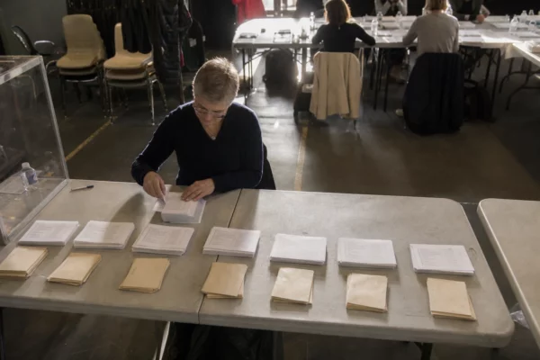 Des bulletins de vote de liste sont triés sur une table lors d’un scrutin sénatorial en mairie.