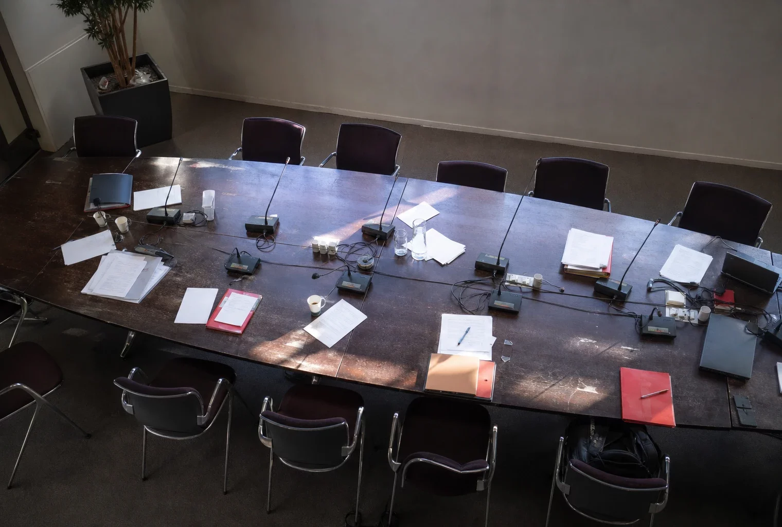 Salle de réunion du bureau national du PS avec table, micros et chaises vides.