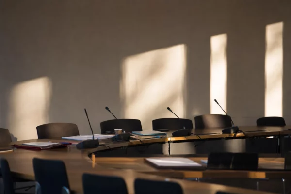 Salle de réunion du bureau national socialiste avec table, micros et dossiers, pour illustrer une décision interne.