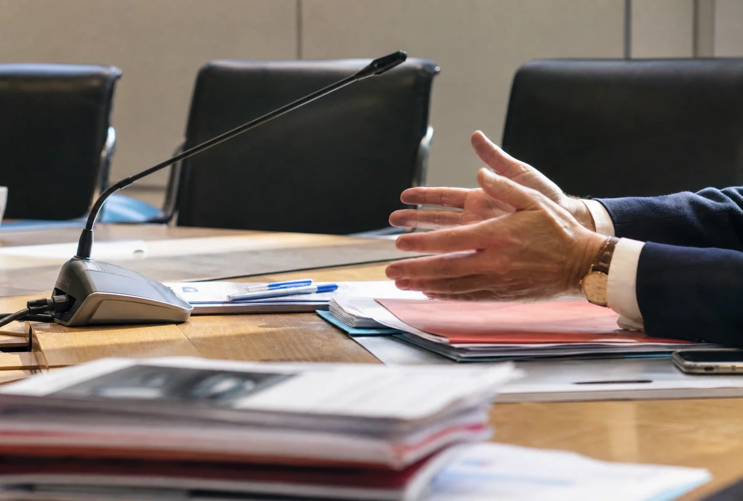 Salle de réunion d’un parti avec table, micros et dossiers, dans le siège parisien où se prépare une décision interne.