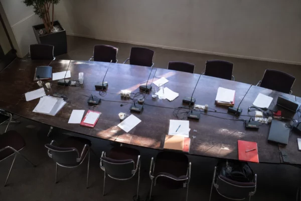 Salle de réunion du bureau national du PS avec table, micros et chaises vides.