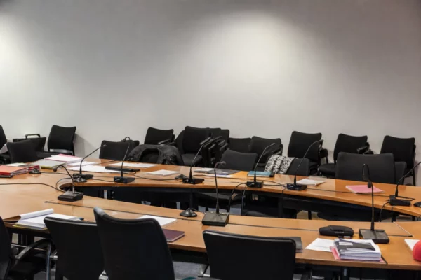 Salle de réunion vide avec tables, micros et chaises alignées, dans le siège d’un parti politique à Paris.