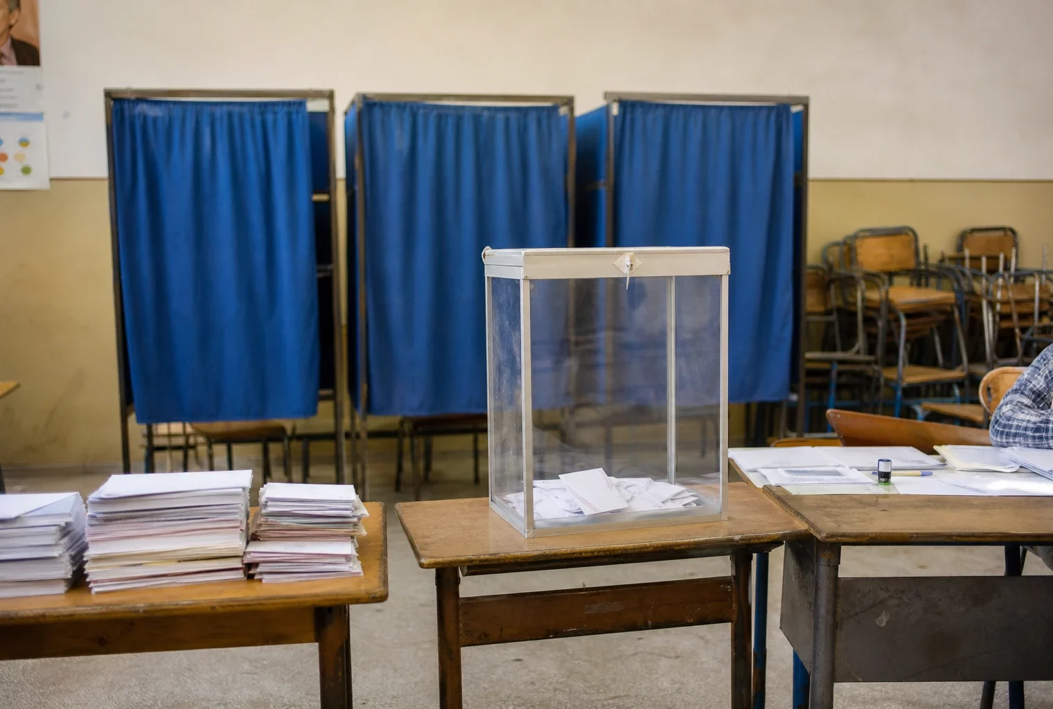 Un bureau de vote au Maroc avec isoloirs, urne et tables de dépouillement, image sobre d’un scrutin législatif.