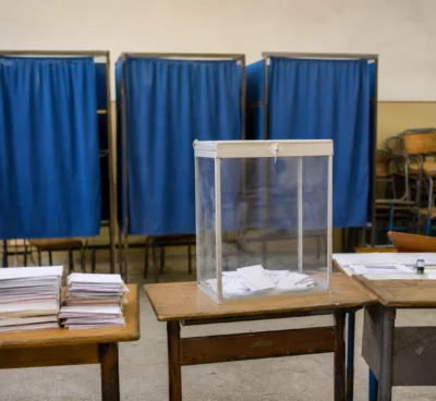 Un bureau de vote au Maroc avec isoloirs, urne et tables de dépouillement, image sobre d’un scrutin législatif.