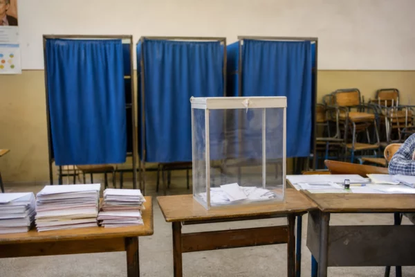 Un bureau de vote au Maroc avec isoloirs, urne et tables de dépouillement, image sobre d’un scrutin législatif.