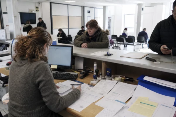 Dans une agence CAF, un comptoir avec dossiers et formulaires illustre le recouvrement des pensions alimentaires.