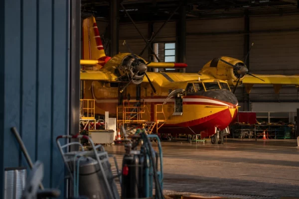 Un avion bombardier d’eau dans un hangar de maintenance, avec du matériel technique autour.