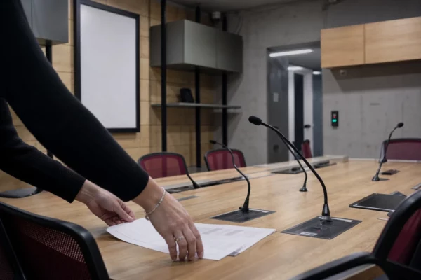 Salle de réunion sobre au centre des congrès Robert-Schuman, table en bois, chaises vides et lumière grise de pluie.