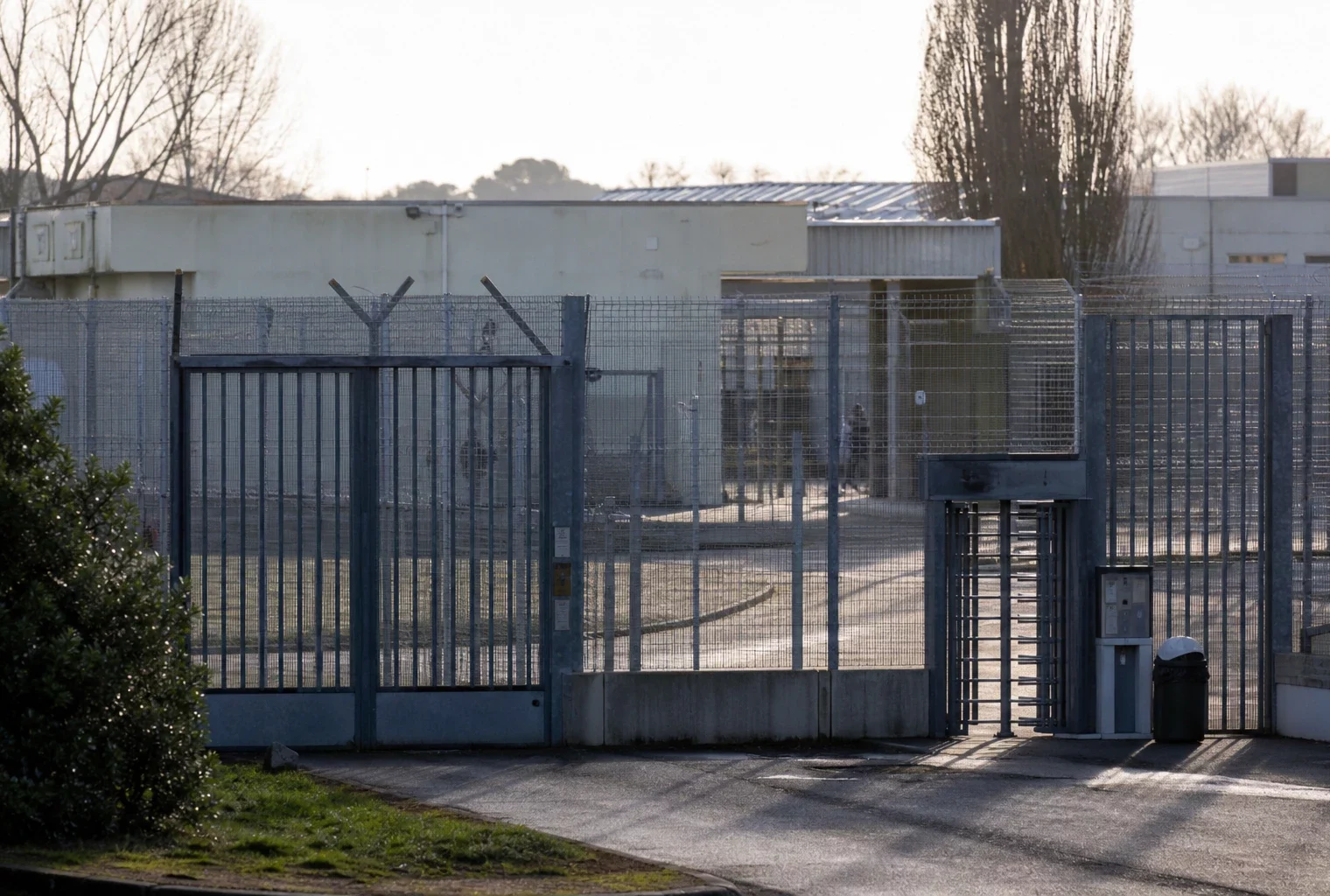 Vue d’un centre de rétention administrative avec clôtures et accès sécurisé, en France.