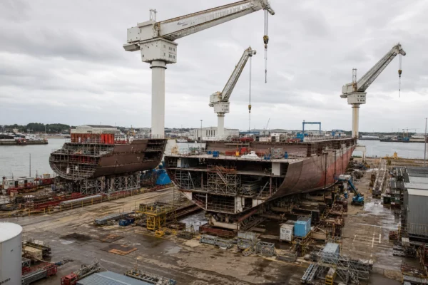 Vue d’un chantier naval à Saint-Nazaire, avec grues, quais et structures métalliques de construction.