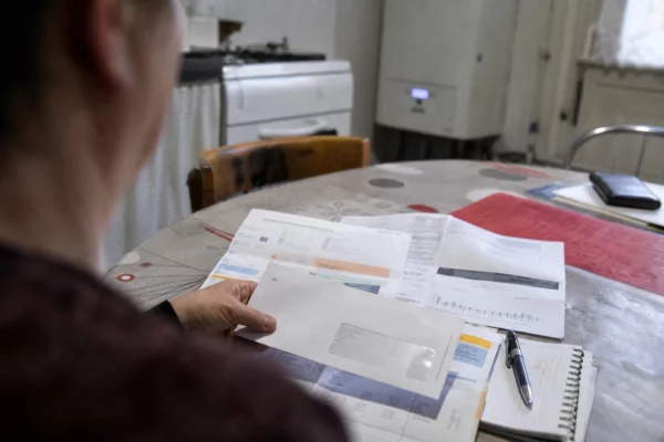Une enveloppe de chèque énergie posée sur des factures d’électricité et de gaz dans une cuisine modeste.