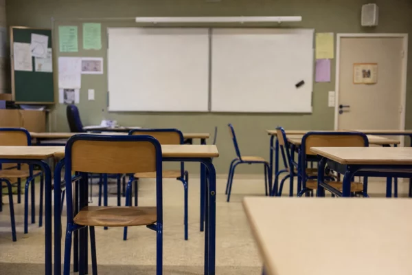 Salle de classe vide avec pupitres et tableau, illustrant l’interdiction de campagne électorale pendant les cours.