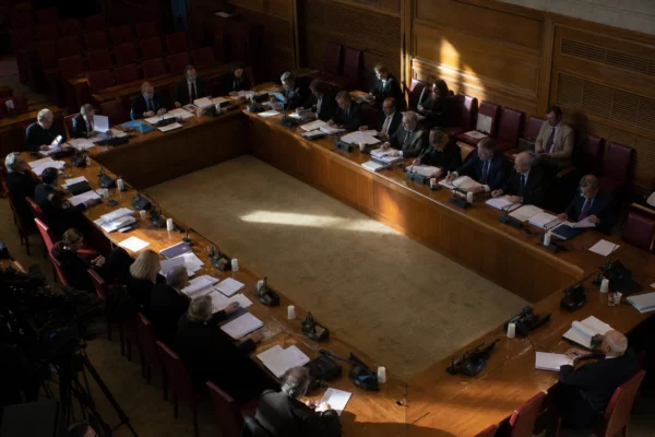 Salle de commission de l’Assemblée nationale avec tables, micros et dossiers autour des députés.