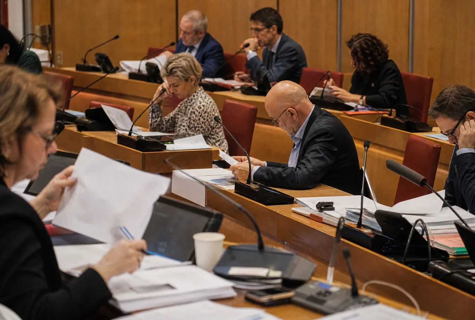 Salle de commission à l’Assemblée nationale avec micros et dossiers, où les députés examinent un texte sur les violences sexuelles.