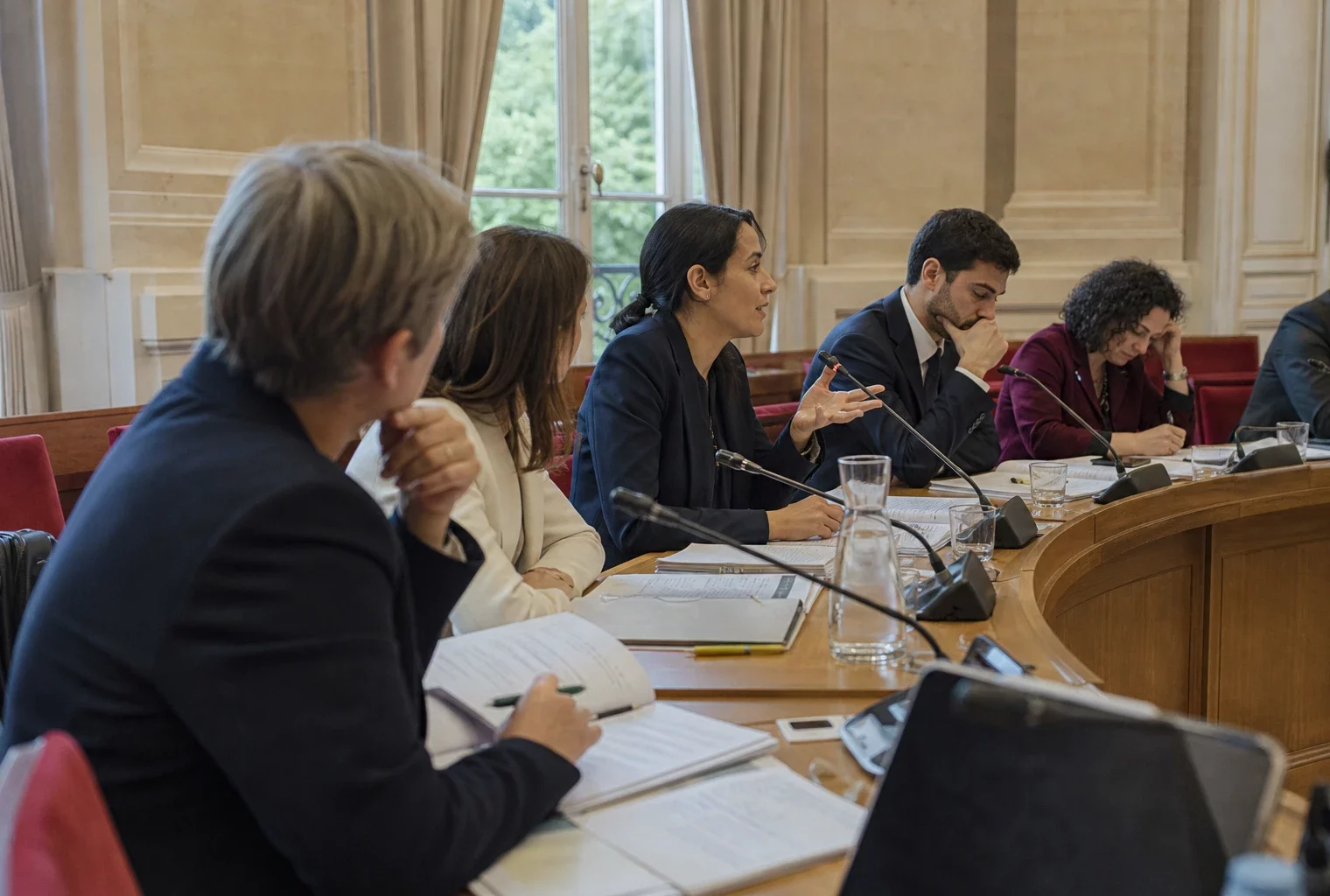 Réunion de commission parlementaire française sur le voile, avec élus anonymes, micros et dossiers autour d’une table
