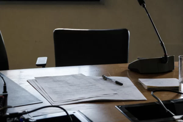 Des feuilles d’un communiqué politique sont posées sur une table de réunion, avec un stylo et quelques notes autour.
