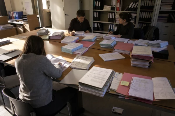 Des dossiers de comptes de campagne empilés sur une table dans un bureau de contrôle administratif.