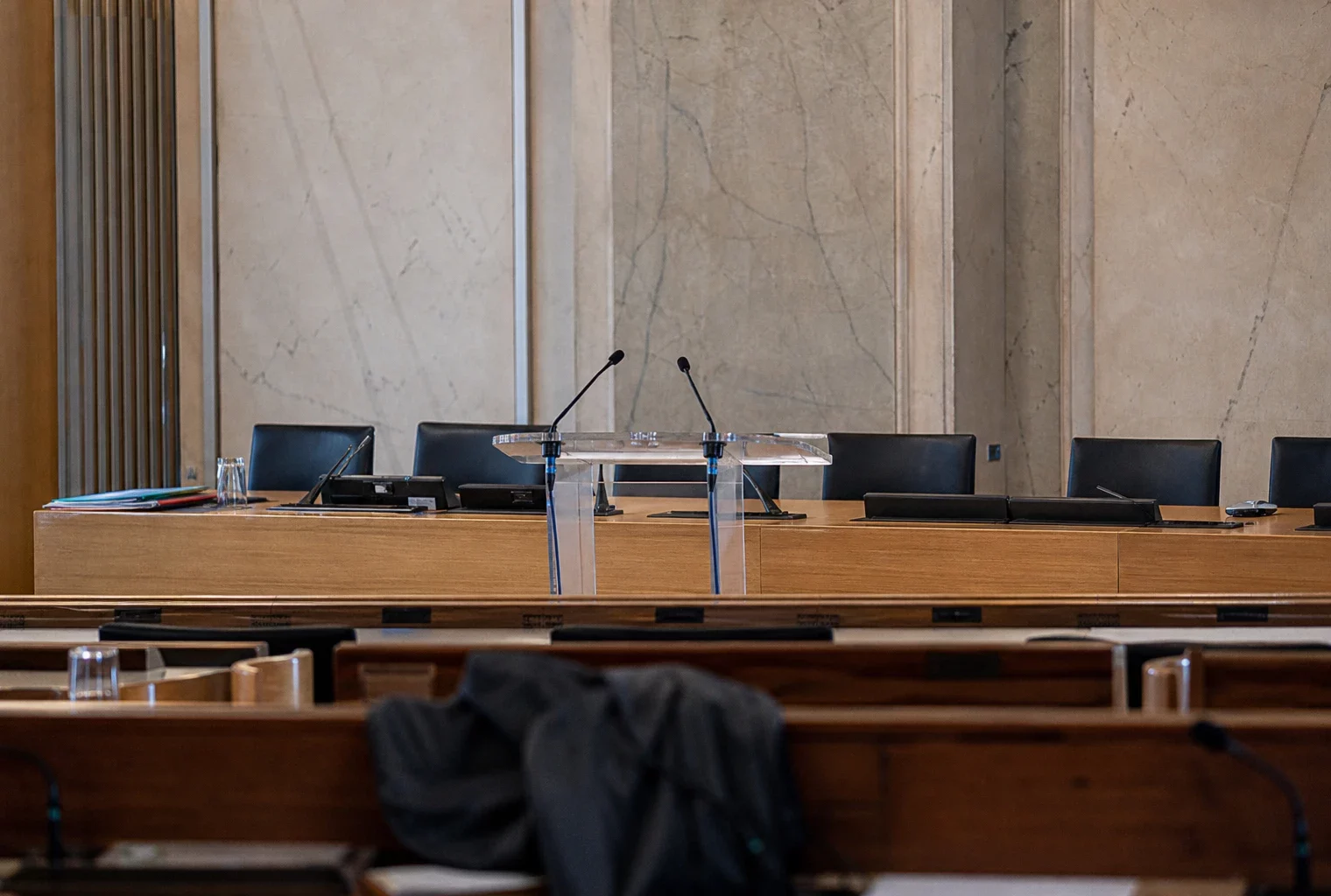 Salle de conférence de presse à l’Assemblée nationale, avec pupitre, micros et rangées de sièges vides.