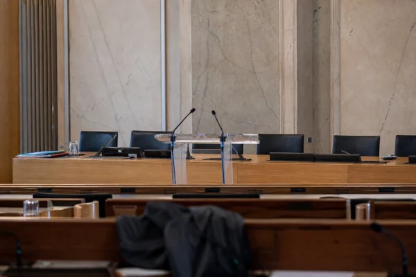 Salle de conférence de presse à l’Assemblée nationale, avec pupitre, micros et rangées de sièges vides.