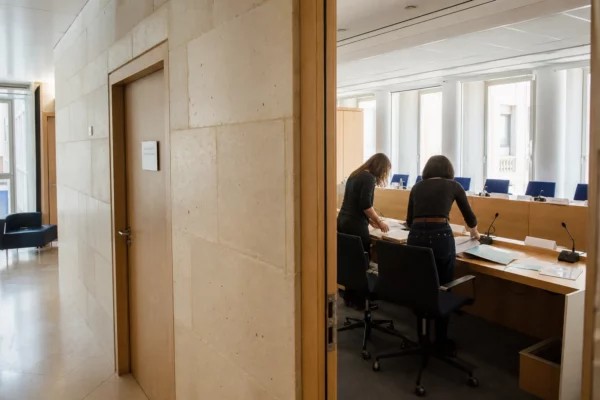 Hall clair d’une institution française avec salle d’audition et agents anonymes préparant des dossiers