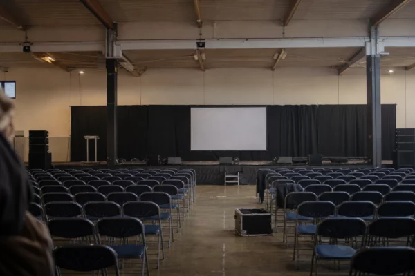 Salle de congrès à Orléans avec rangées de chaises, pupitre et estrade, prête pour un meeting politique.