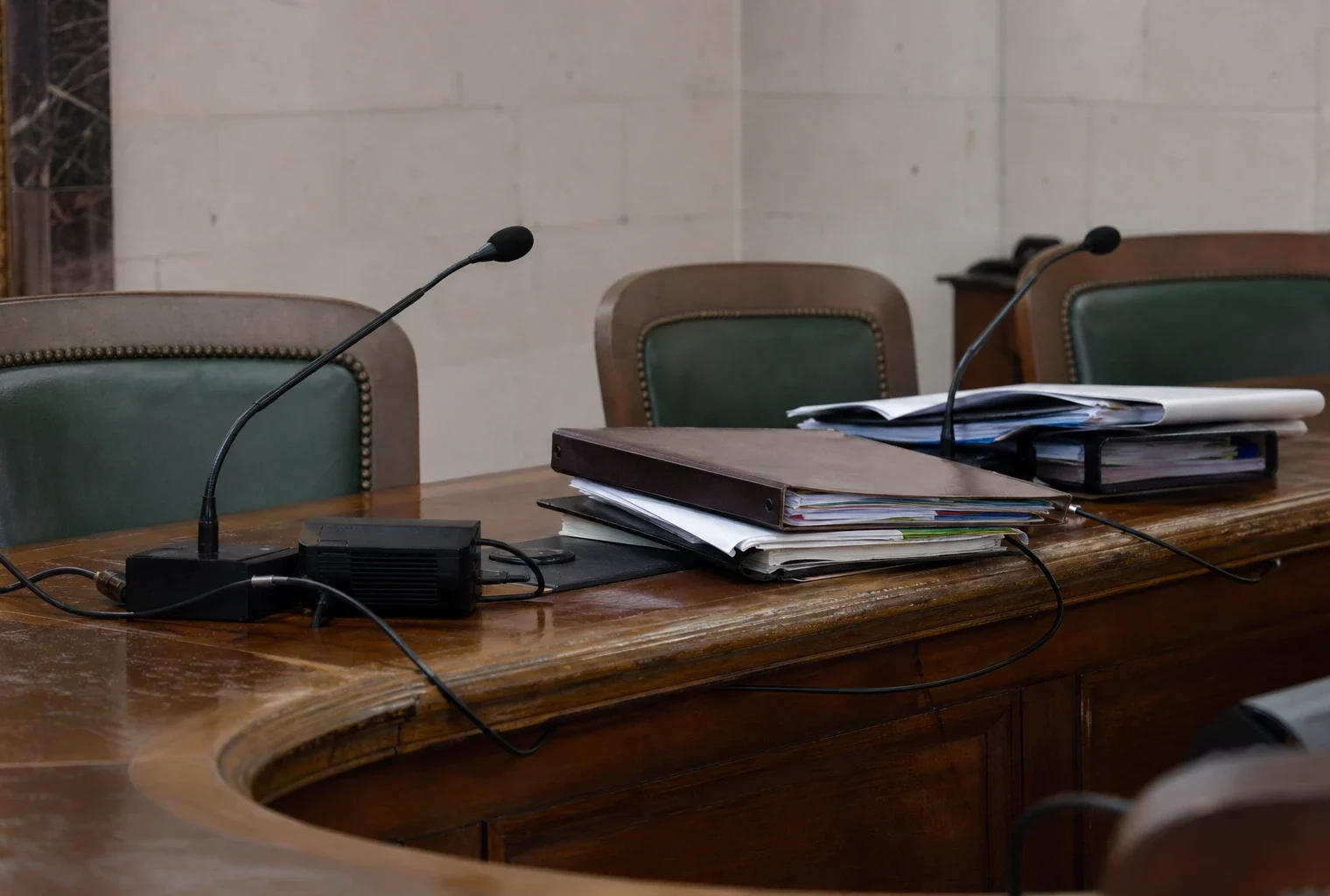 Salle du Conseil constitutionnel avec sièges vides, table de séance et dossiers empilés.