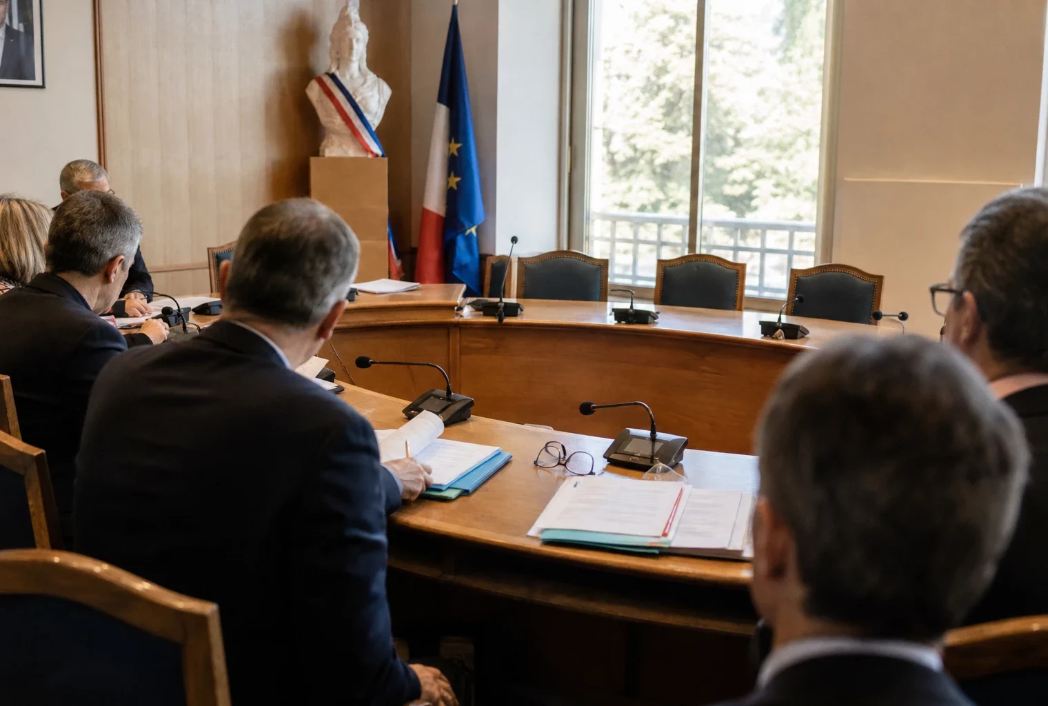 Salle municipale française avec chaise vide, micros et dossiers lors d’un briefing sur l’affaire de Leipzig