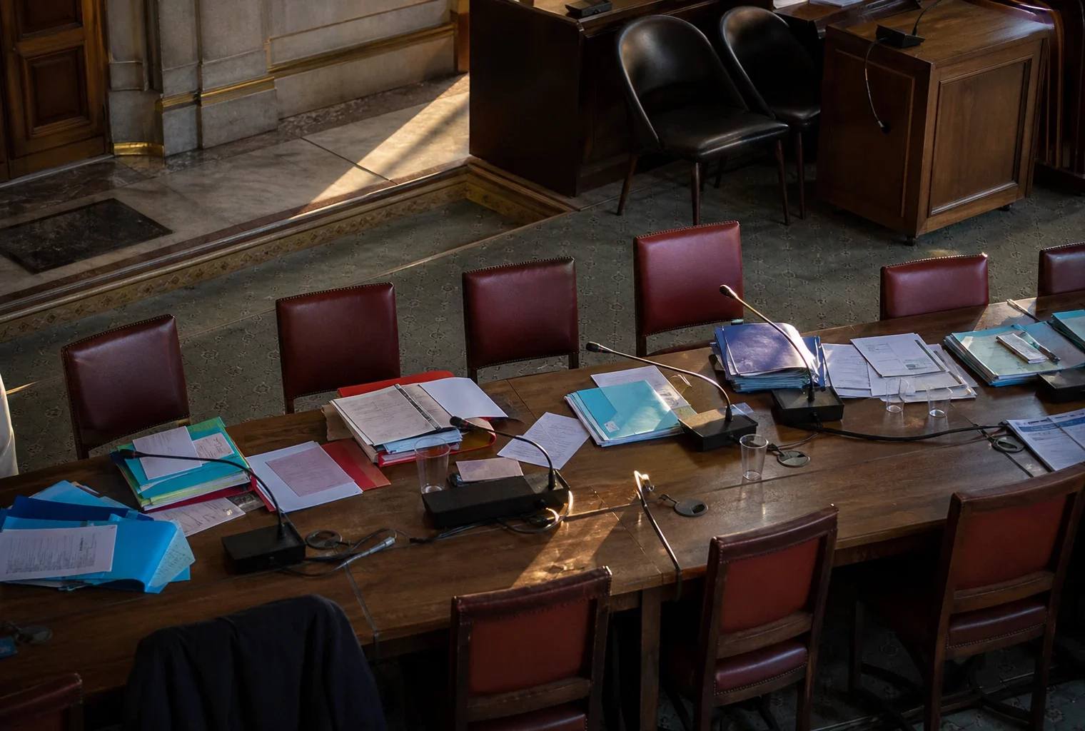 Salle de réunion à l’Assemblée nationale avec tables, chaises et dossiers pour des consultations sur le budget.