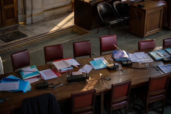 Salle de réunion à l’Assemblée nationale avec tables, chaises et dossiers pour des consultations sur le budget.
