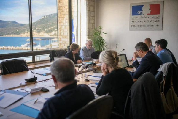 Salle municipale française en réunion sur la crise migratoire à Ceuta, avec micros, dossiers et une chaise vide