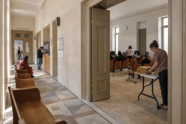 Hall clair d’une institution publique française avec une salle d’audition et des visiteurs anonymes en arrière-plan