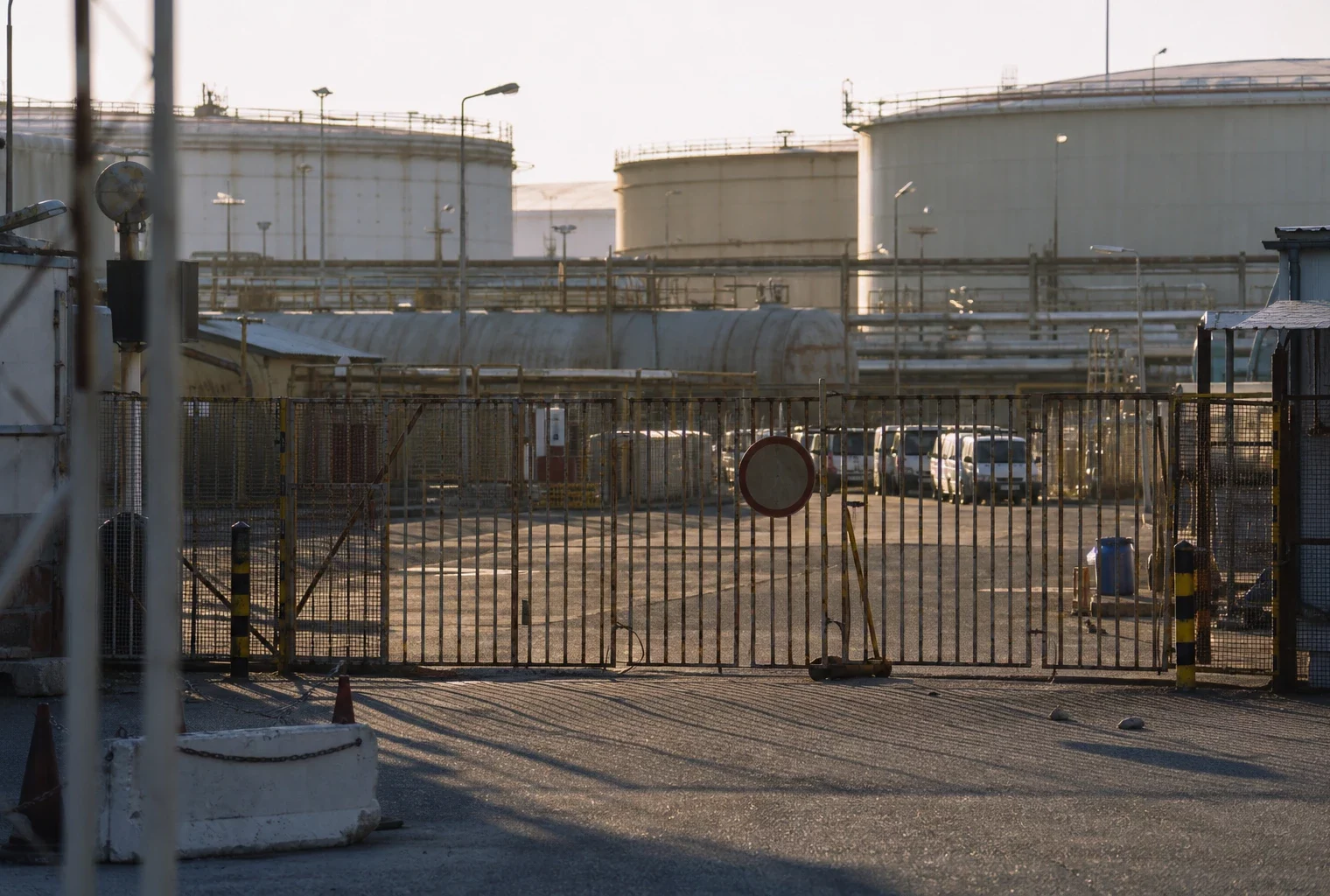 Dépôt pétrolier fermé dans un port méditerranéen, avec cuves et accès barré.