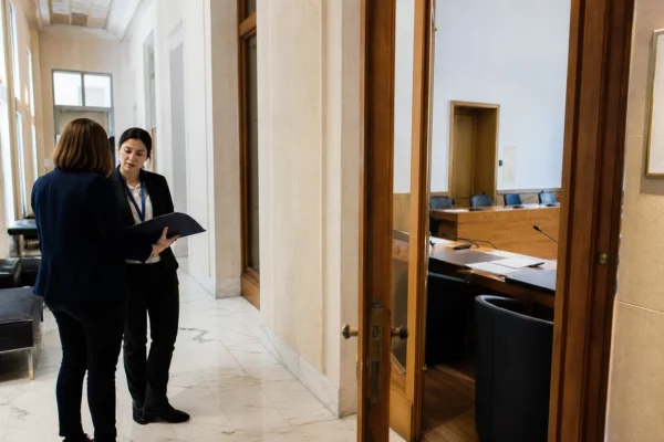 Hall clair d’une institution française, avec des agents anonymes et une salle d’audition évoquant le contrôle de la dette publique