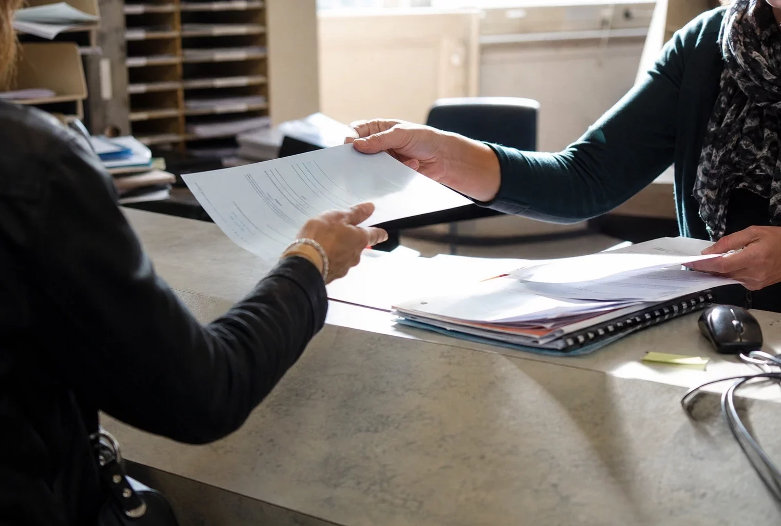 Guichet de demande de logement social avec formulaires et dossiers dans un service administratif.