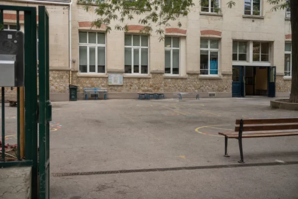 Devant une école parisienne, la cour et le portail rappellent le cadre des temps périscolaires des enfants.