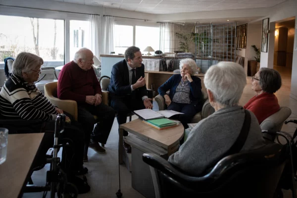 Dans un Ehpad, des résidents échangent avec un candidat à la présidentielle dans une salle commune.