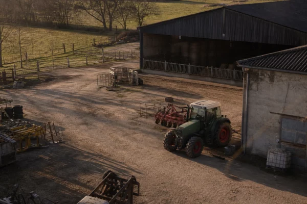 Dans une exploitation agricole, un tracteur et du matériel rangé rappellent le cadre concret des débats sur l’écologie.