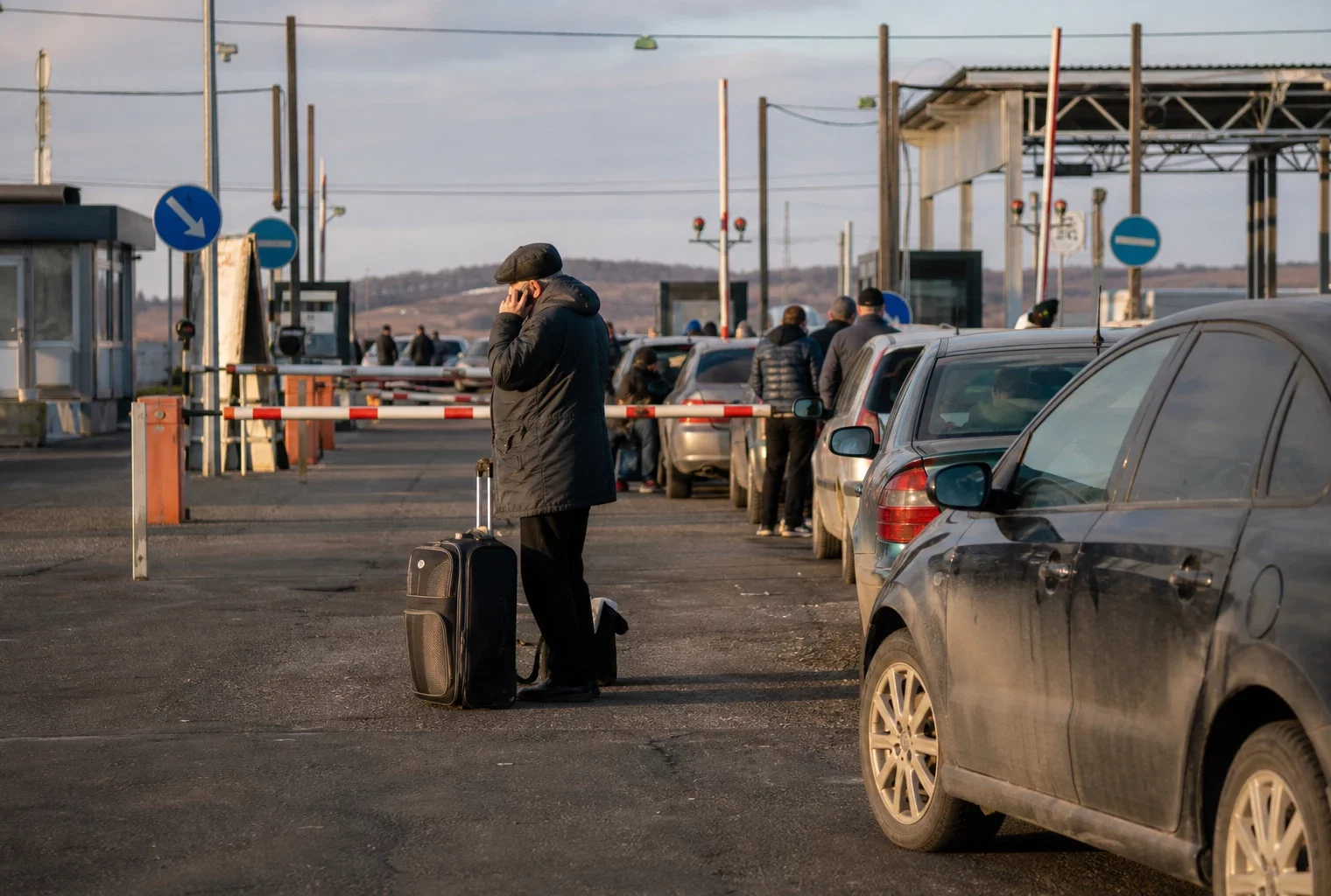 File de voitures et de voyageurs à un poste frontière, évoquant l’exode provoqué par une mobilisation.