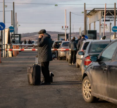 File de voitures et de voyageurs à un poste frontière, évoquant l’exode provoqué par une mobilisation.